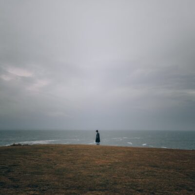 Foto von Josh Hild A person standing on a hill overlooking the ocean