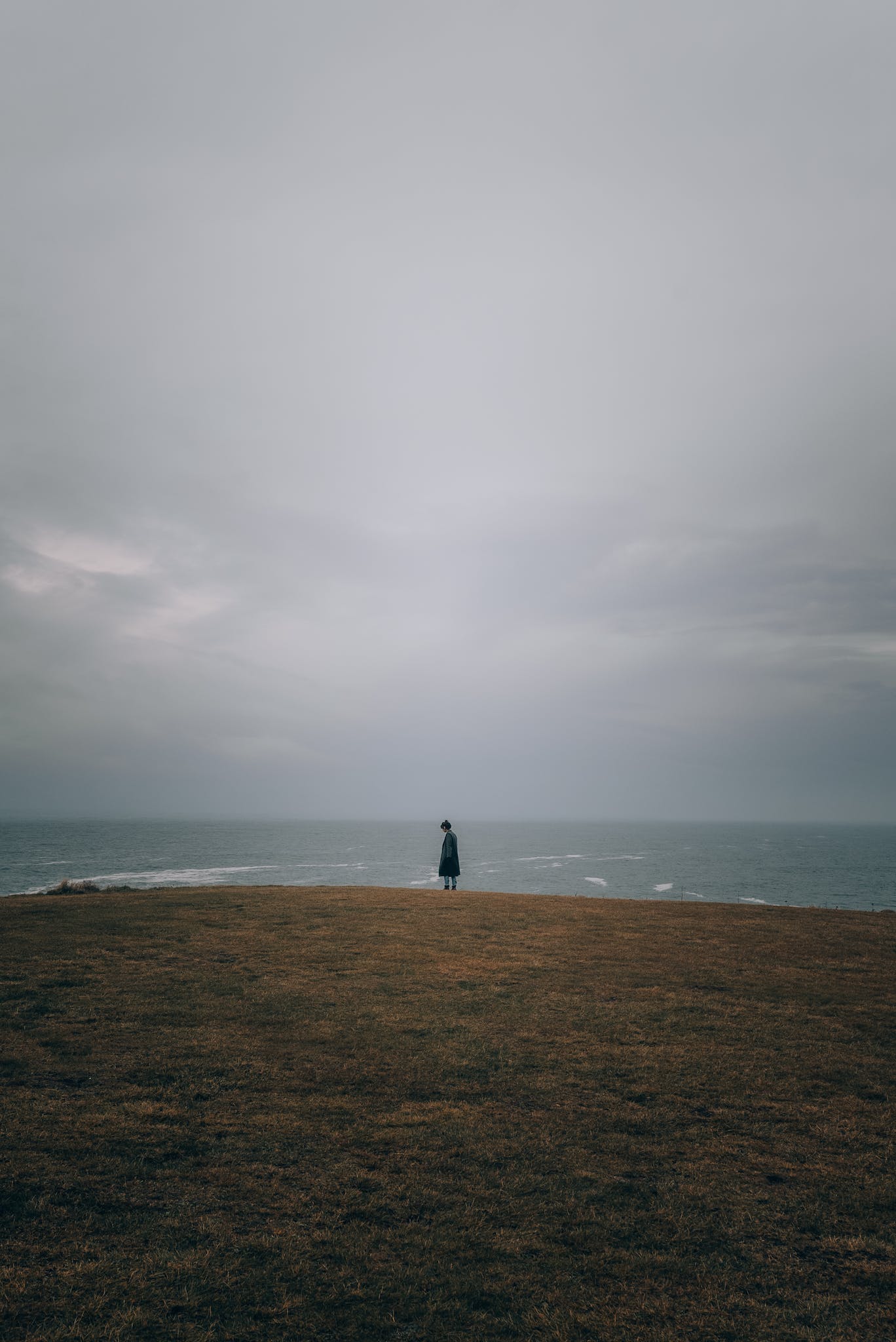 Foto von Josh Hild A person standing on a hill overlooking the ocean