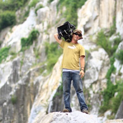 Man Standing on Rock While Holding Black Case