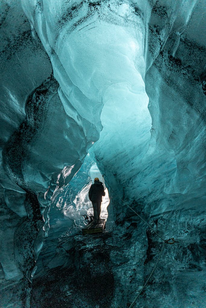 Person Walking in an Ice Cave in a Glacier